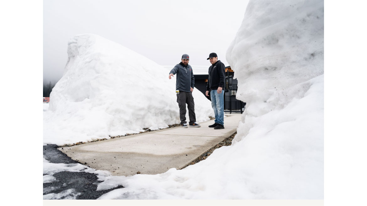 Snoqualmie gets up to 20-feet of snow per year. Two men standing in between two large snowpiles.