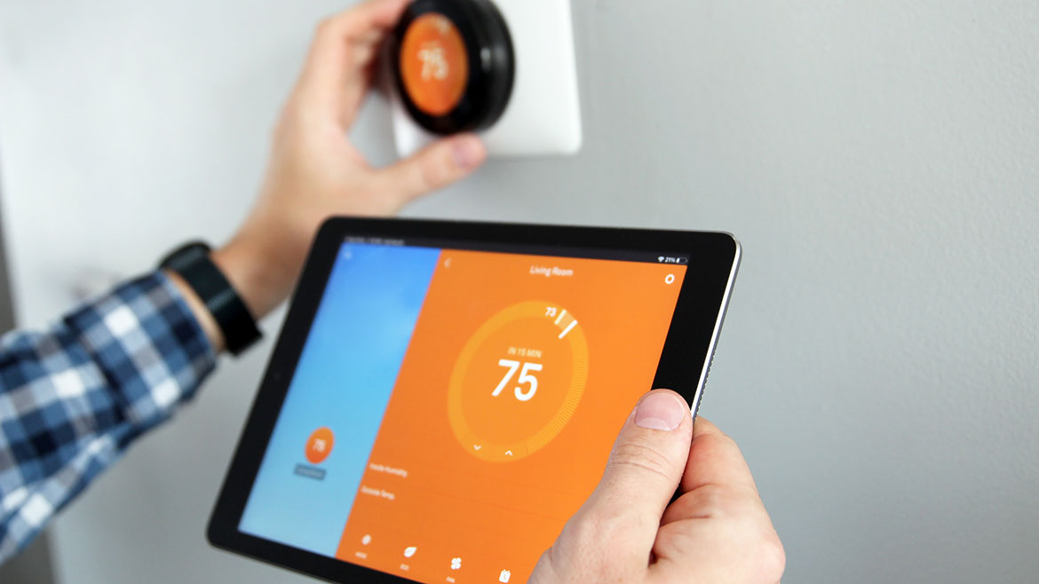 Man is Adjusting a temperature using a tablet with smart home app in modern living room.